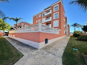 A multi-story residential building with balconies, a paved walkway, and a white fence. - Aroma de Mar - Terrace, pool & comfort in Dénia (Dénia)