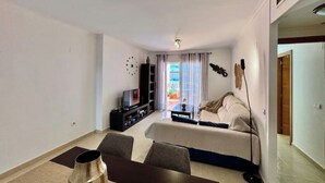 Una camera d'albergo moderna con divano, televisore, libreria e zona pranzo.
