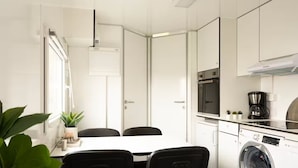 A compact kitchen with a washing machine, a coffee maker, and a microwave. - Mobile Home Park (Strendur)
