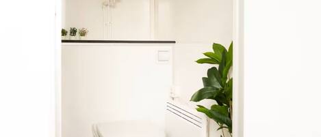 Un baño pequeño y blanco con inodoro, radiador y calentador de agua instalado en la pared.