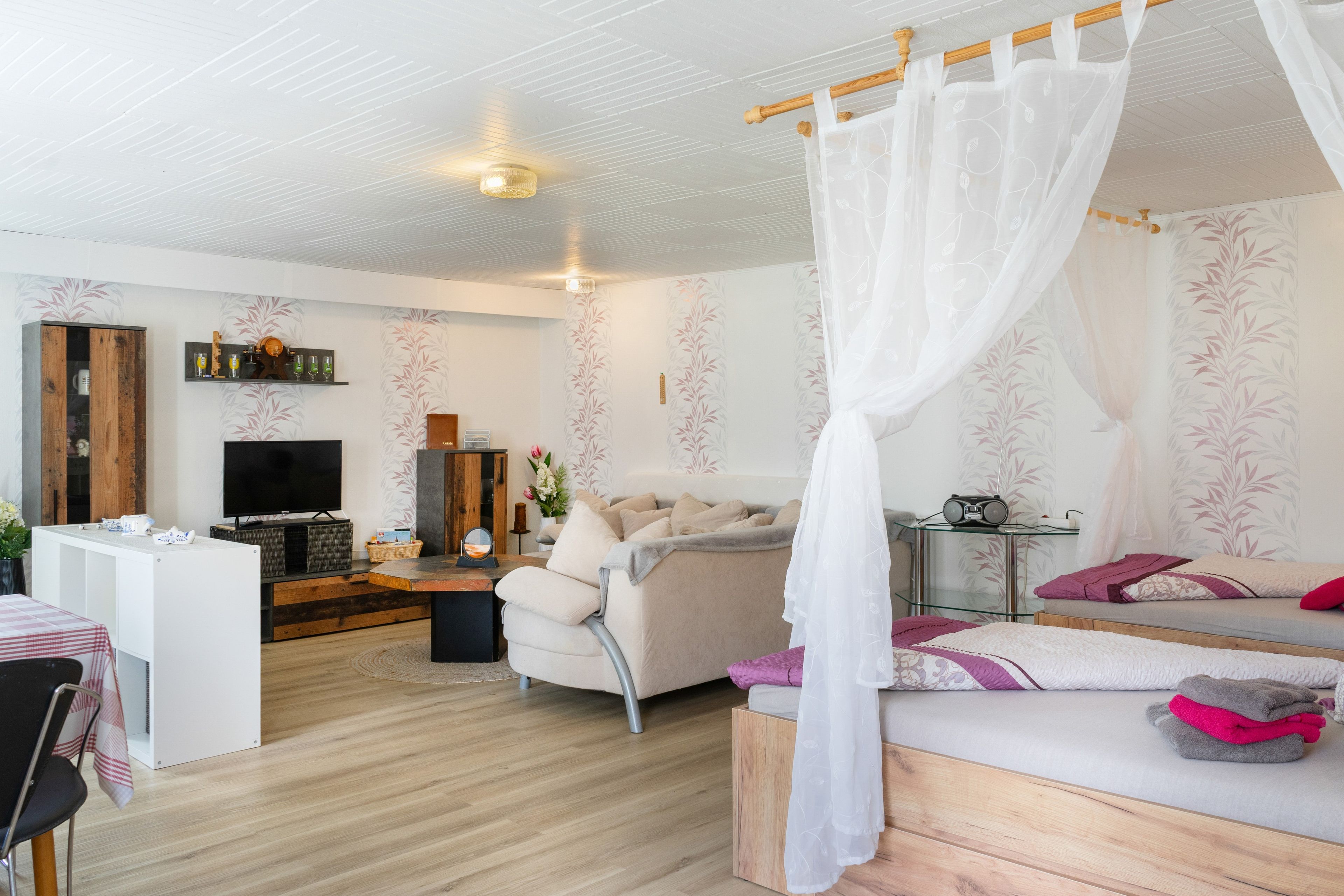 Ein modernes Schlafzimmer mit Bett, Fernseher, Schreibtisch und Badebereich.