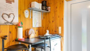A kitchen with wooden walls, a coffee machine, a clock, and a heart-shaped decoration.