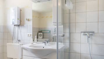 A bathroom with a sink, mirror, shower, and toilet.