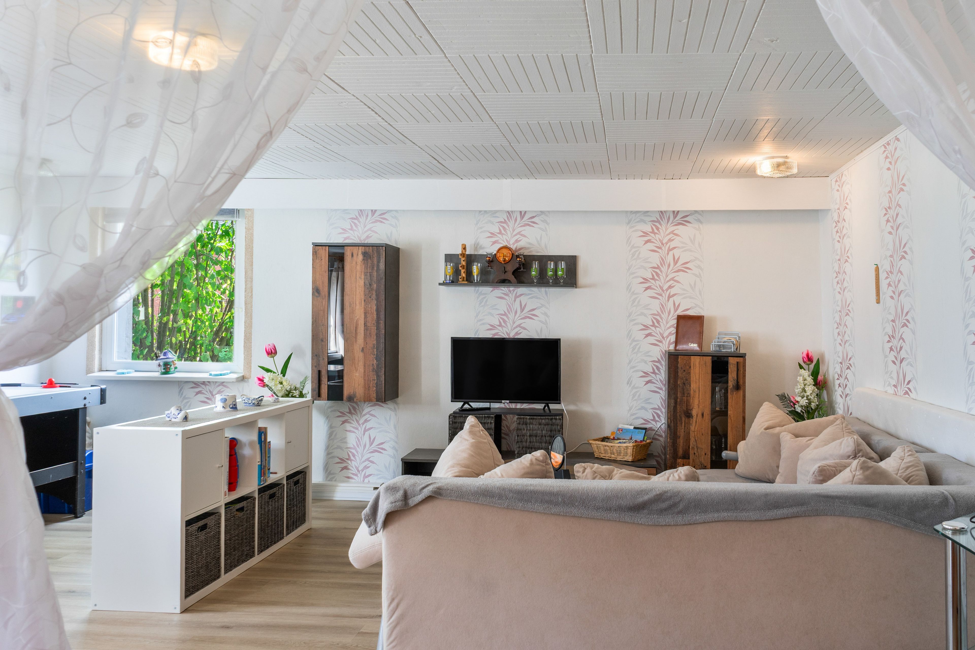 A modern living room with a flat-screen TV, a sofa, a coffee table, and a dining area with a small kitchen.