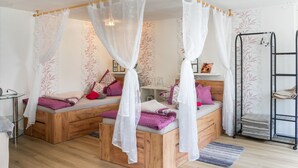 A bedroom with a wooden bed, a bedside table, a nightstand, a wall-mounted shelf, and a black metal rack. - Holiday Home Fechter with Shared Terrace, Garden, and Wi-Fi in Lanz (Lanz)