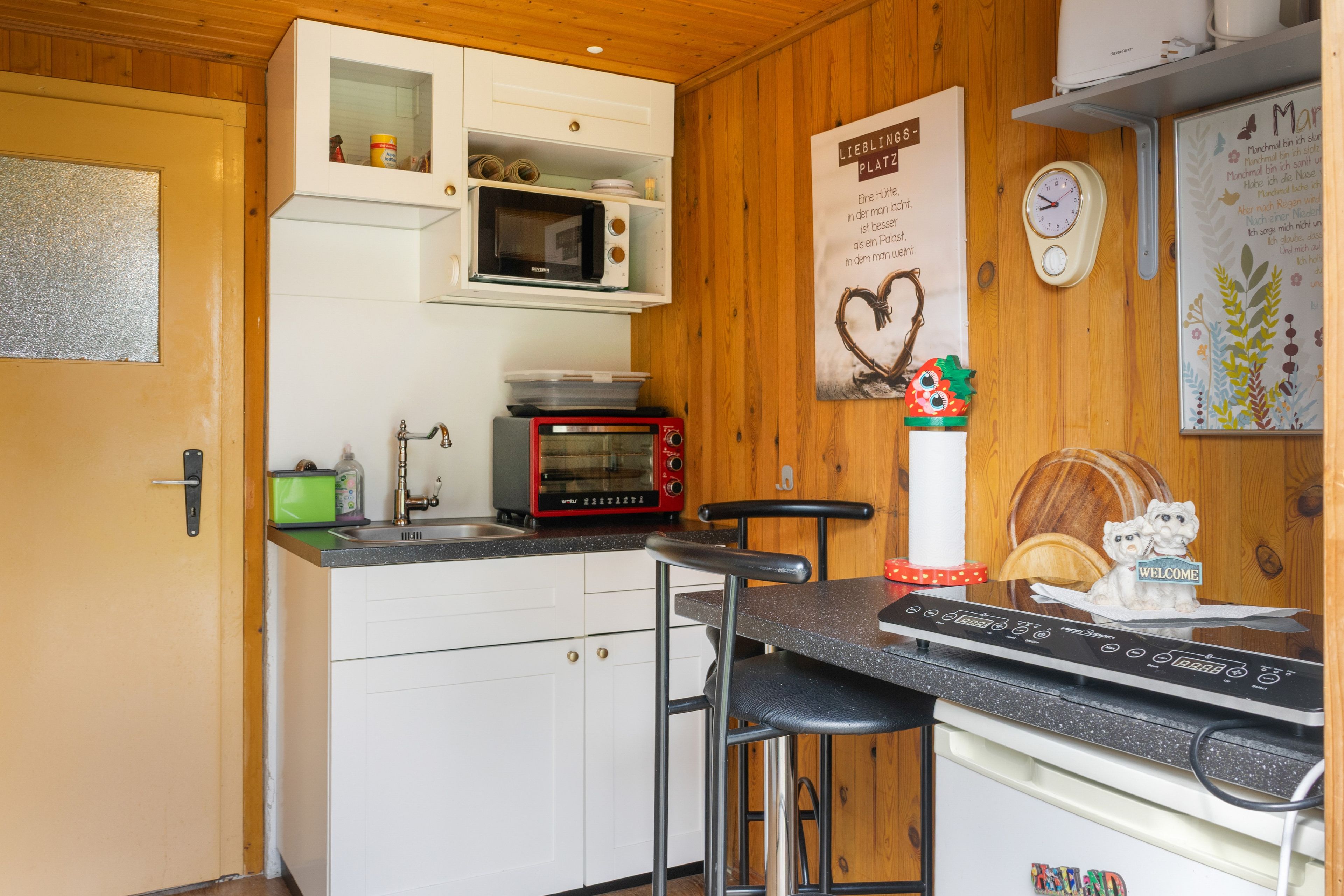 Eine Küche mit weißen Schränken, einer Mikrowelle, einem Toaster und einer Kaffeemaschine.