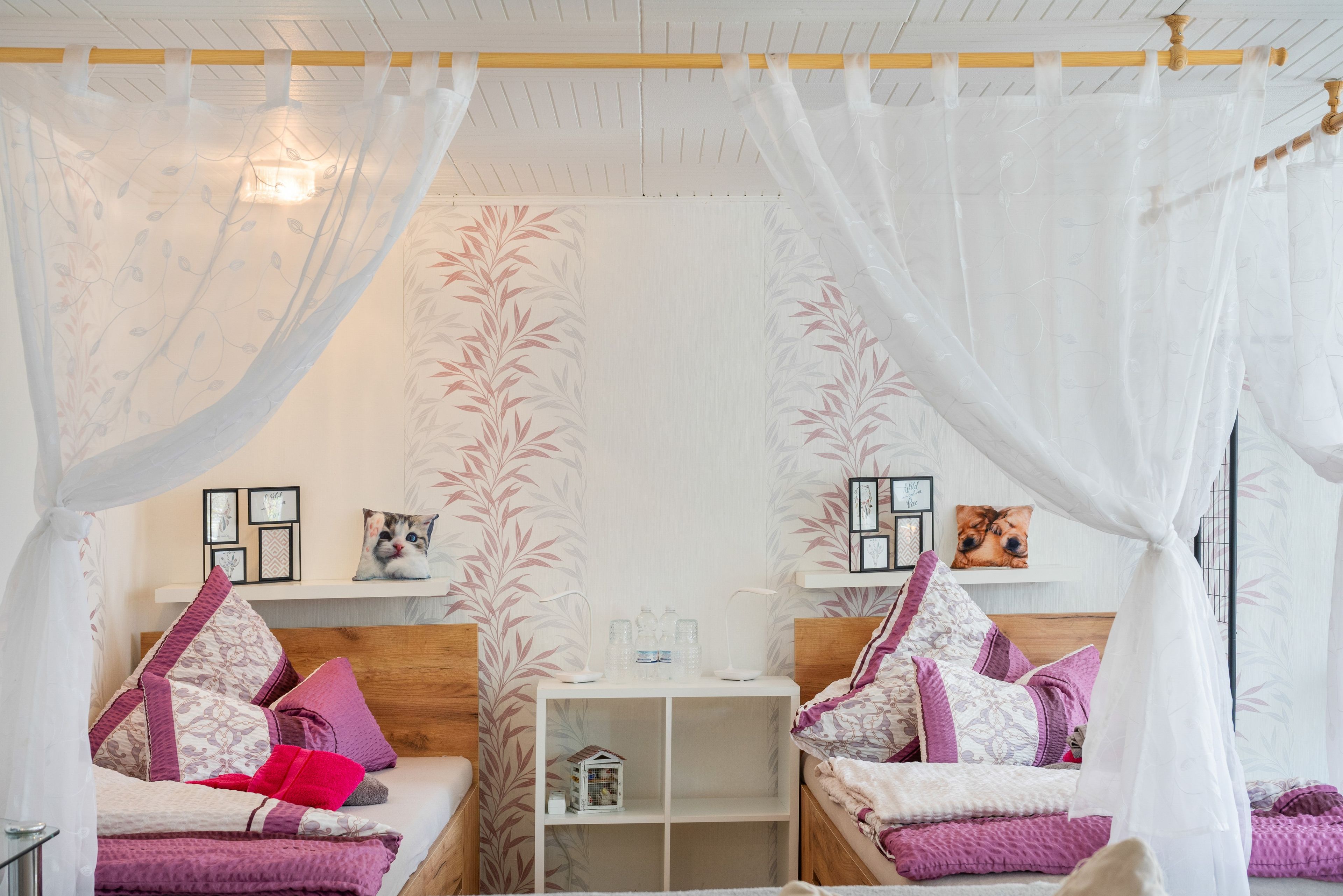 Une chambre à coucher avec un lit à baldaquin, une table de chevet avec une lampe et une étagère ornée d’objets décoratifs.