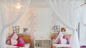 Une chambre à coucher avec un lit à baldaquin, une table de chevet avec une lampe et une étagère ornée d’objets décoratifs.