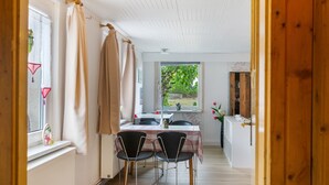 A room with a dining table, chairs, a window with curtains, and a view of greenery outside. - Holiday Home Fechter with Shared Terrace, Garden, and Wi-Fi in Lanz (Lanz)