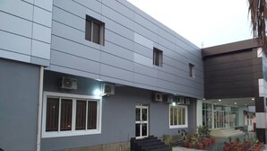 A modern building with a grey facade, large windows, and a paved entrance area with potted plants. - Adunola Serviced  Apartment  (Lagos)