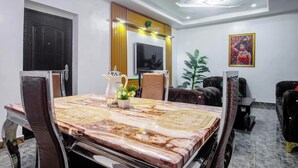 A conference room with a marble table, leather chairs, a coffee pot, and a television on the wall. - Adunola Serviced  Apartment  (Lagos)