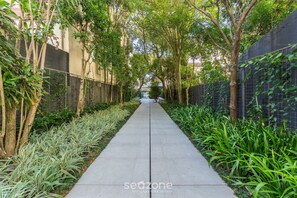 A pathway flanked by lush greenery and trees, leading to a building in the distance. - Condominium w/ Complete Leisure Facilities and Unbeatable Location in POA - Bles (Porto Alegre)