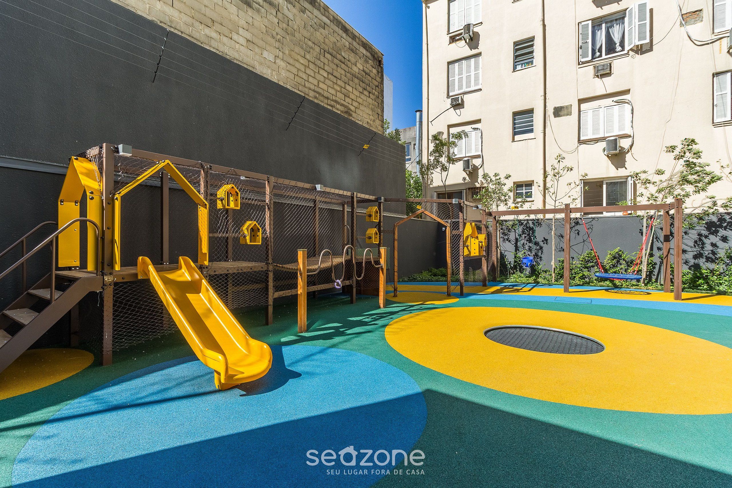 An outdoor play area with a slide, climbing structures, and a circular soft play zone.