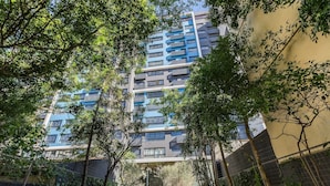 A multi-story residential building with balconies, surrounded by trees and a fence. - Condominium w/ Complete Leisure Facilities and Unbeatable Location in POA - Bles (Porto Alegre)