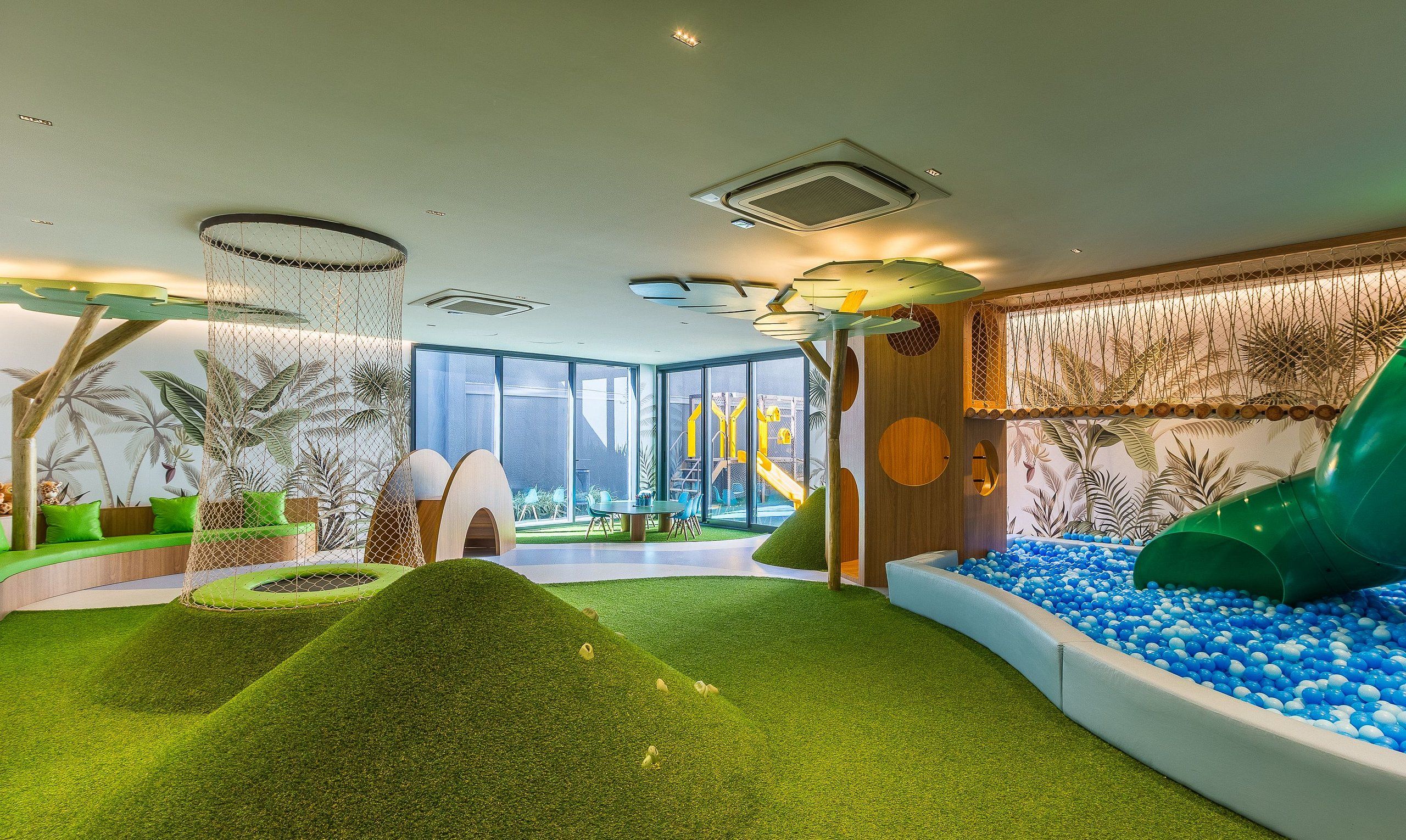 A children's play area with a slide, ball pit, and artificial grass.