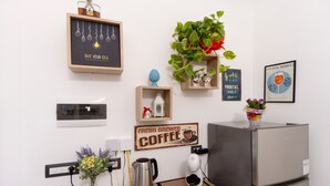 Een keuken met een koffiezetapparaat, waterkoker en een koelkast.