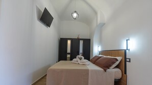 Een slaapkamer met een bed, een aan de muur bevestigde televisie, een lamp en een kledingkast.