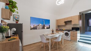 Een moderne keuken met houten kastjes, een eettafel met stoelen, een wasmachine en een koelkast.