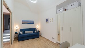 Een kamer met een blauwe bank, een witte kast en een schilderij aan de muur.