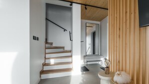 A modern interior with a wooden staircase, a round table with a globe, and a fluffy white object on a pedestal.