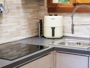 Eine moderne Küche mit eingebautem Herd, einem Kooper-Wasserspender und einer Spüle aus Edelstahl.