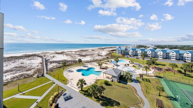 Un resort con vista a la playa, varias piscinas y una cancha de tenis.