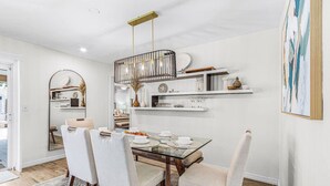 Un coin repas avec une table en verre, quatre chaises et un lustre.