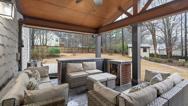 An outdoor patio with wicker furniture, a ceiling fan, and a view of the backyard. - Mall of GA, Cozy 5 Bedrooms Gateway, Sleep 12 + Game Room and Wi-Fi (Buford)