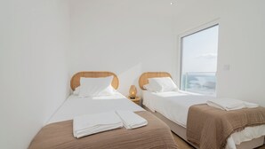 Ett hotellrum med två separata sängar, var och en med en brun sänggavel, vita sängkläder och ett fönster med utsikt över himlen.