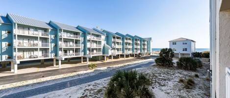 Un hôtel situé en bord de mer, doté de nombreux balcons, d’une plage de sable et offrant une vue dégagée sur l’océan.
