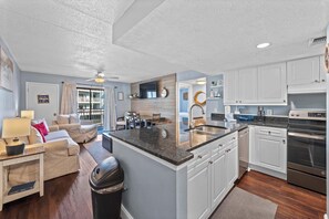 A modern kitchen with white cabinets, a granite countertop, and stainless steel appliances.