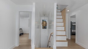 Ein modernes Interieur mit Treppe, Holzboden und einer hängenden Leuchte.