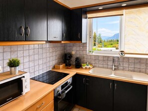 A modern kitchen with dark cabinets, a window with a view, a sink, and a stove. - Villa Morea With Pool Near Chania City (Mournies)