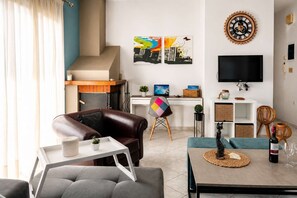 A modern living room with a sofa, a dining table, a TV, and artwork on the wall. - Villa Morea With Pool Near Chania City (Mournies)