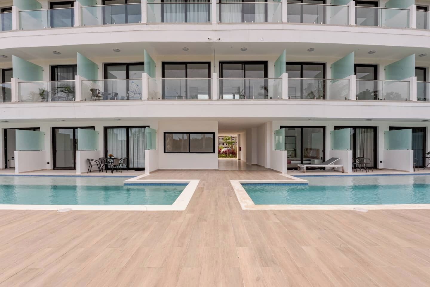 Un edificio moderno de varios pisos con piscina central, balcones y puertas de vidrio.