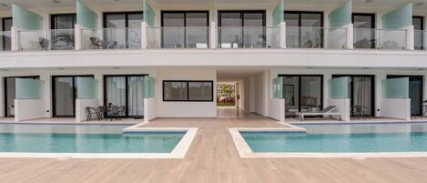 Un edificio moderno de varios pisos con piscina central, balcones y puertas de vidrio.