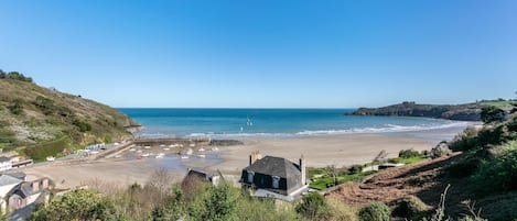 A coastal view with a beach, houses, and a clear sky.