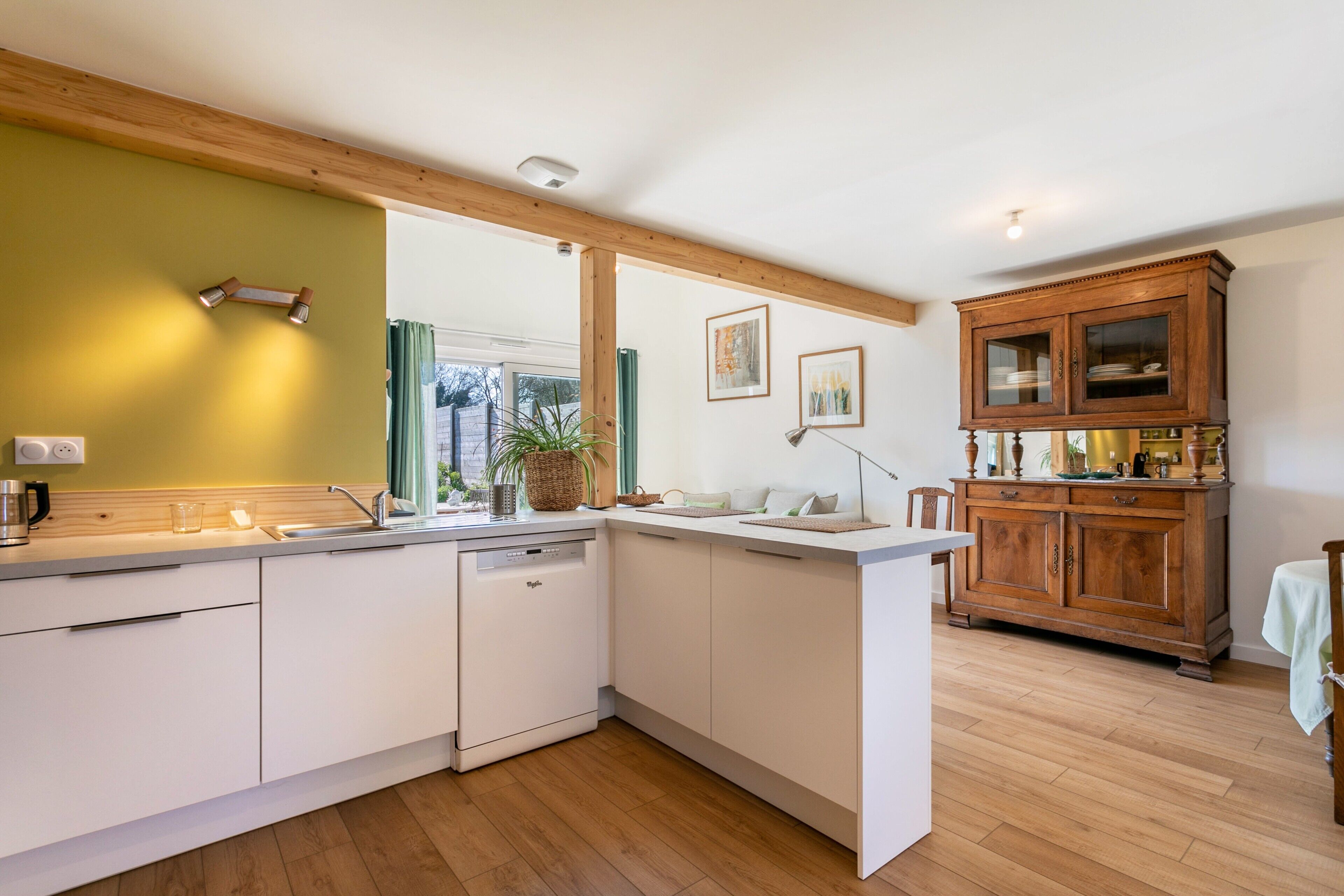 A modern kitchen with white cabinets, a dishwasher, and wooden beams on the ceiling.