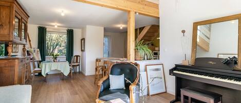 Un vaste salon comprenant un piano, un coin repas et un escalier menant à l’étage supérieur.