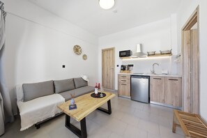 A compact living space with a sofa, a wooden table, a kitchen area with a microwave, and a dishwasher. - Holiday Home 'One Bedroom Apartment with Veranda' with Balcony, Wi-Fi and Air Conditioning (Melitiei)