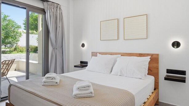 Un dormitorio moderno con una cama grande, un ventanal corredero a un balcón y dos cuadros en la pared.