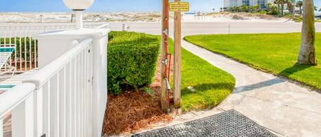Una entrada cerrada con detector de metales, una cerca blanca, y una vista despejada de una carretera y una playa al fondo.