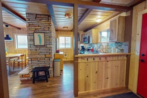 A wooden interior with a stone fireplace, wooden cabinets, and a red door.
