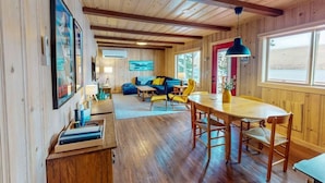 A wooden interior with a sofa, yellow chairs, a dining table, and a painting on the wall. - Prop House | Wallowa lakefront home w/dock (Joseph)