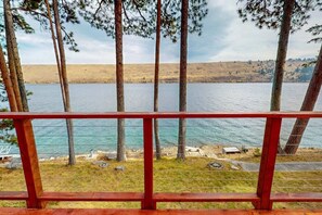A view of a lake with trees and a red railing in the foreground. - Prop House | Wallowa lakefront home w/dock (Joseph)