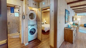 A wooden interior with a washing machine, a bed, and a small kitchenette. - Prop House | Wallowa lakefront home w/dock (Joseph)