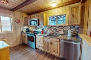 A kitchen with wooden cabinets, a microwave, stove, and sink.