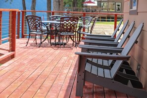 A wooden deck with outdoor seating, including chairs and a table.