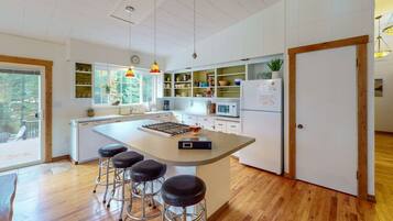 A modern kitchen with a central island, bar stools, and built-in shelves.