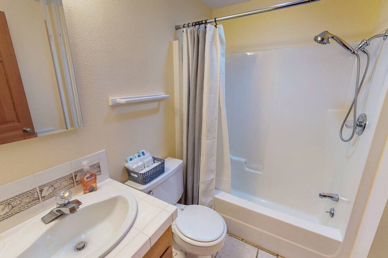 A bathroom with a sink, toilet, shower, and a towel rack.